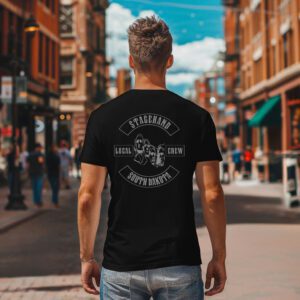 A man stands on a city street, facing away and wearing the South Dakota Stagehand Local Crew Tee featuring a bold graphic on the back.